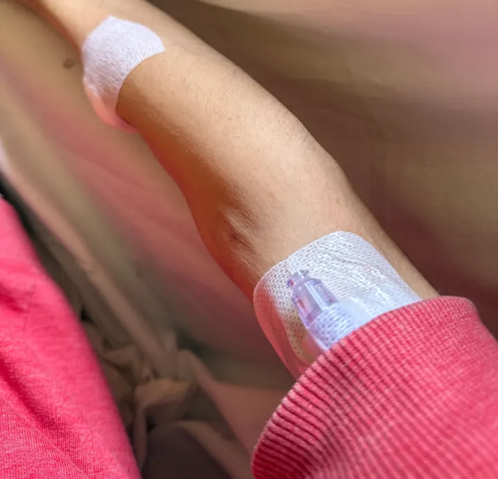 Fotografia tirada pelo fundador durante o internamento: o braço com um cateter endovenoso e pensos, sobre a cama do hospital.
